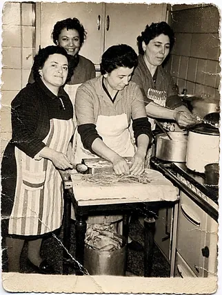 Foto d'epoca: donne in grembiule al lavoro in cucina, mentre preparano la pasta fresca a mano